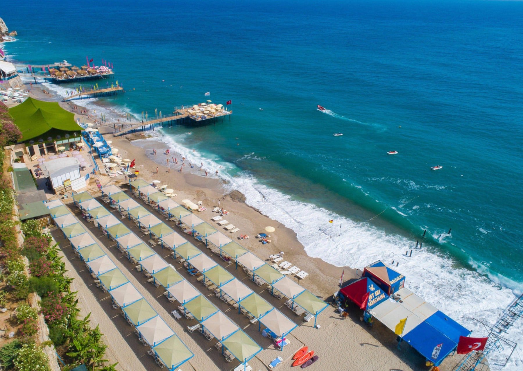 The hotel's private beach at Konaklı seen from above, with rows of parasols and the Mediterranean beyond