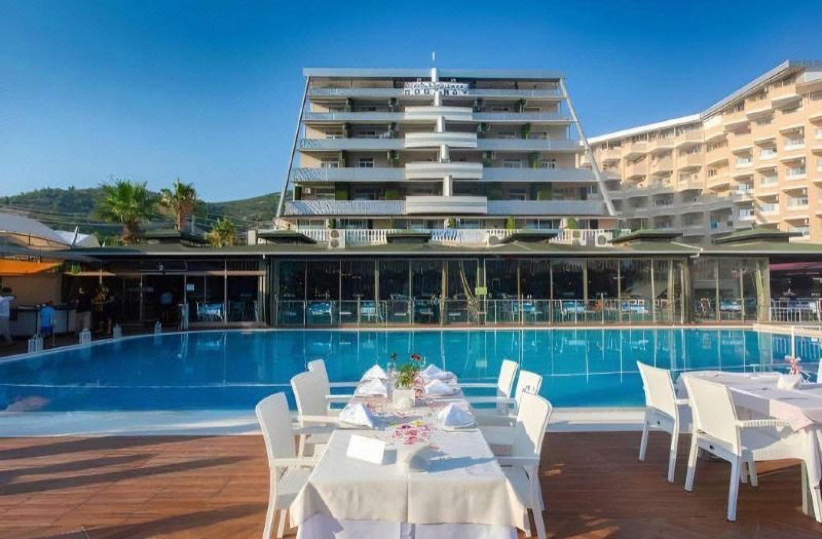 Tables laid beside the pool with the hotel behind